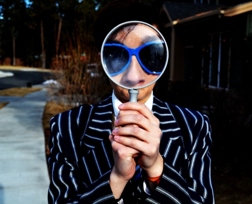 person using magnifying glass enlarging the appearance of his nose and sunglasses
